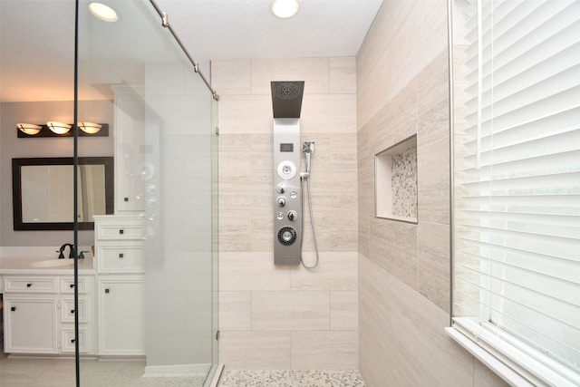 bathroom featuring a tile shower, tile flooring, and vanity