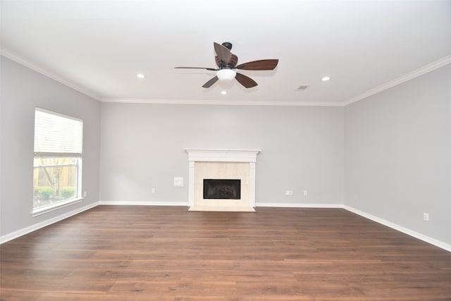 unfurnished living room featuring ornamental molding, dark hardwood / wood-style floors, a tiled fireplace, and ceiling fan