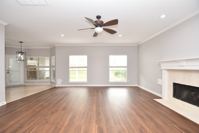 unfurnished living room featuring crown molding, dark wood-type flooring, a high end fireplace, and ceiling fan with notable chandelier