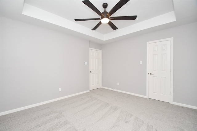 unfurnished room with ceiling fan, a tray ceiling, and carpet floors