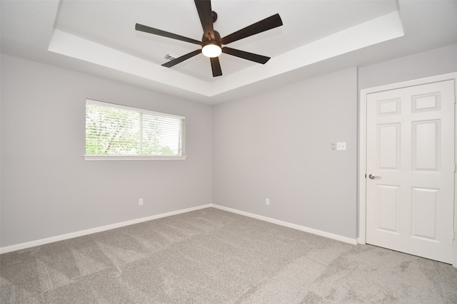 carpeted spare room featuring ceiling fan and a raised ceiling