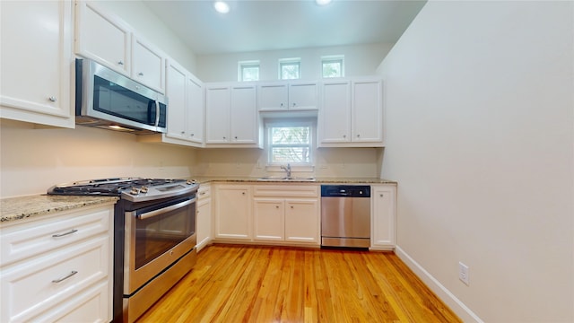 kitchen featuring sink, light hardwood / wood-style flooring, light stone counters, and stainless steel appliances