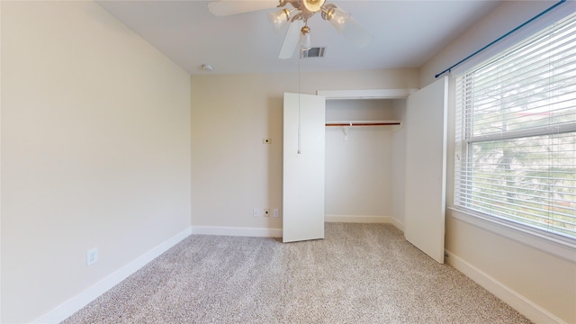 unfurnished bedroom featuring light carpet, multiple windows, and ceiling fan