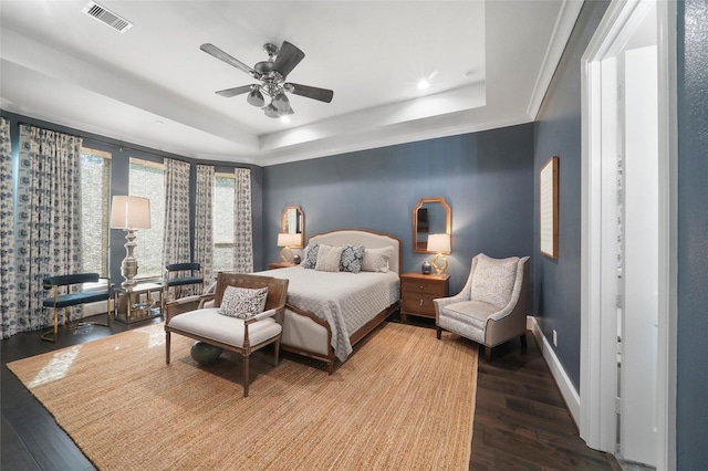 bedroom with hardwood / wood-style floors, a raised ceiling, and ceiling fan