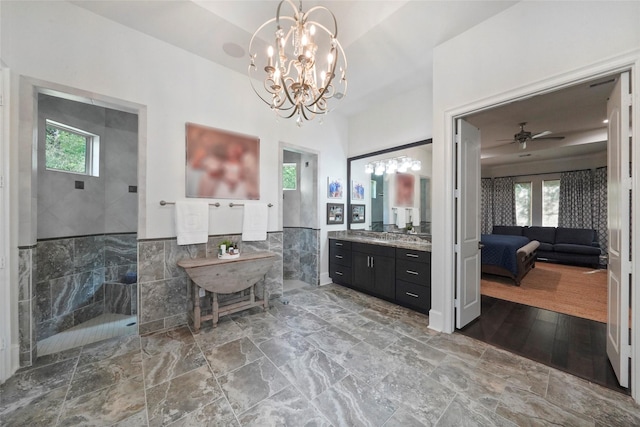 bathroom with vanity, ceiling fan with notable chandelier, tile walls, and a healthy amount of sunlight