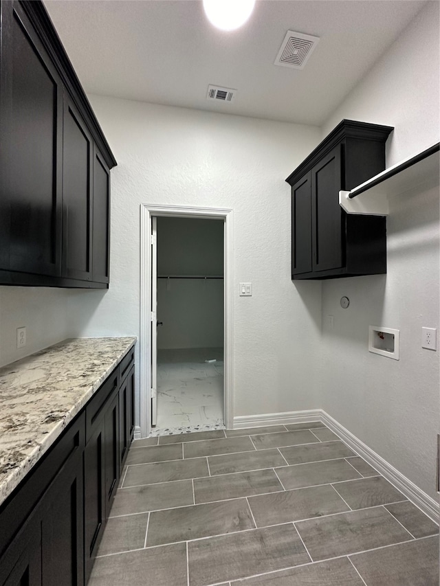 laundry room featuring dark tile patterned flooring, washer hookup, and cabinets