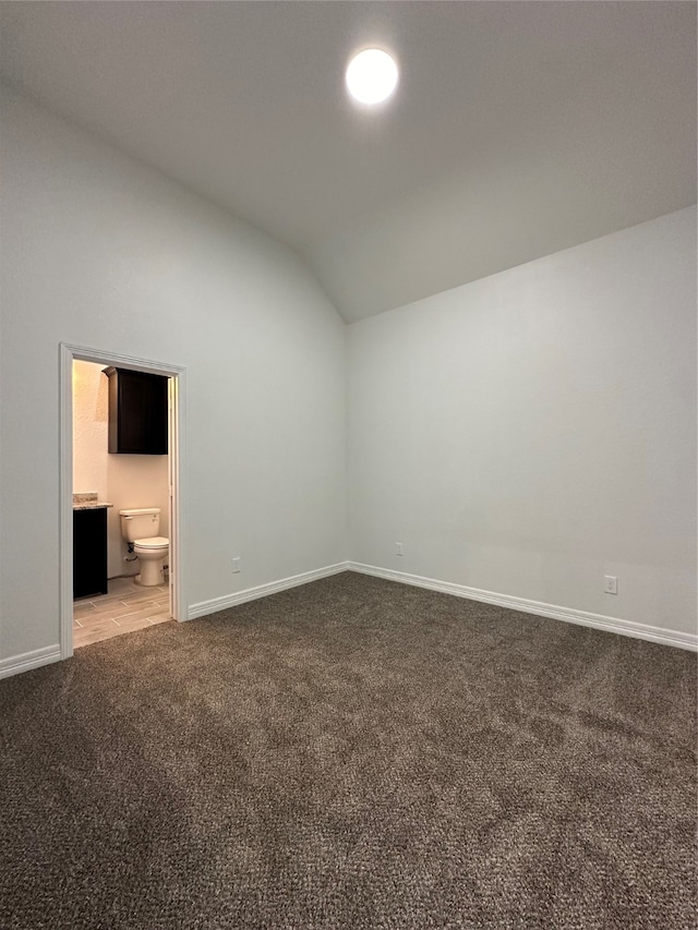 interior space featuring light carpet, ensuite bath, and lofted ceiling