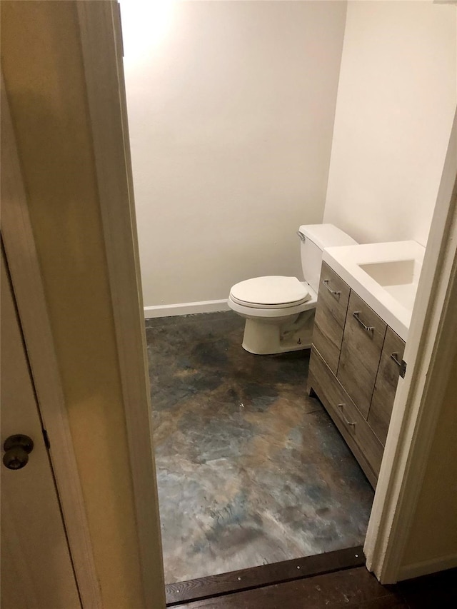 bathroom featuring concrete floors, toilet, and vanity