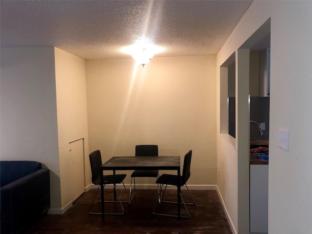 dining area featuring dark wood-type flooring and a textured ceiling