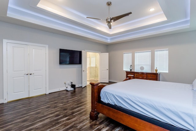 bedroom with ceiling fan, a closet, ensuite bath, dark wood-type flooring, and a raised ceiling