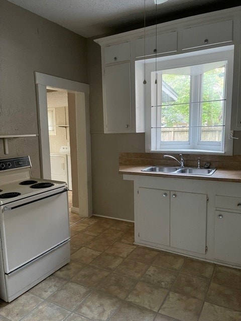 kitchen featuring light tile patterned flooring, white electric range, white cabinets, sink, and washer / clothes dryer