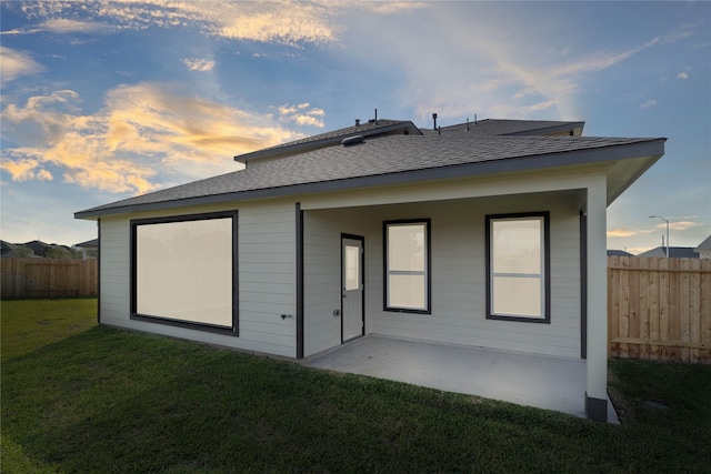 back house at dusk with a lawn