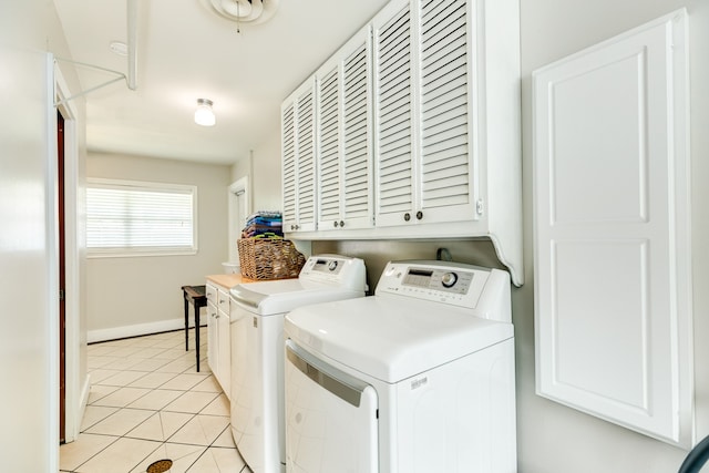 clothes washing area featuring cabinets, washer and clothes dryer, and light tile floors