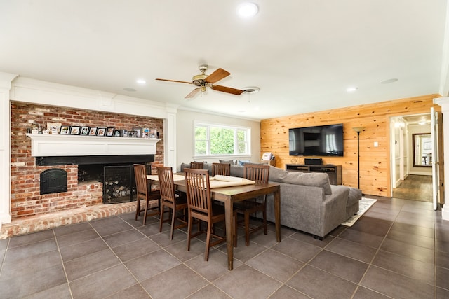 dining room featuring dark tile flooring, ceiling fan, and wooden walls