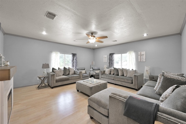 living room with a textured ceiling, ceiling fan, crown molding, and light hardwood / wood-style flooring