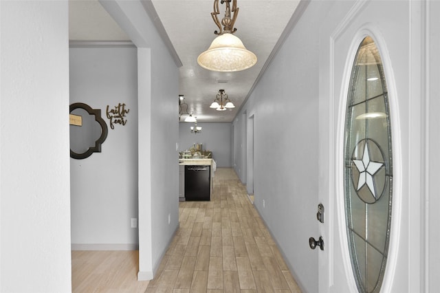 hall with a textured ceiling, ornamental molding, and light hardwood / wood-style floors