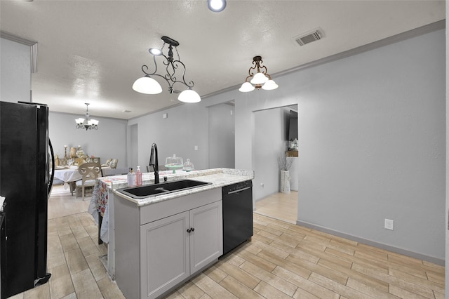 kitchen with black appliances, decorative light fixtures, an inviting chandelier, sink, and a center island with sink