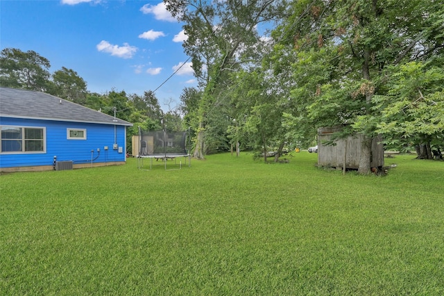 view of yard with central AC unit, a trampoline, and a shed