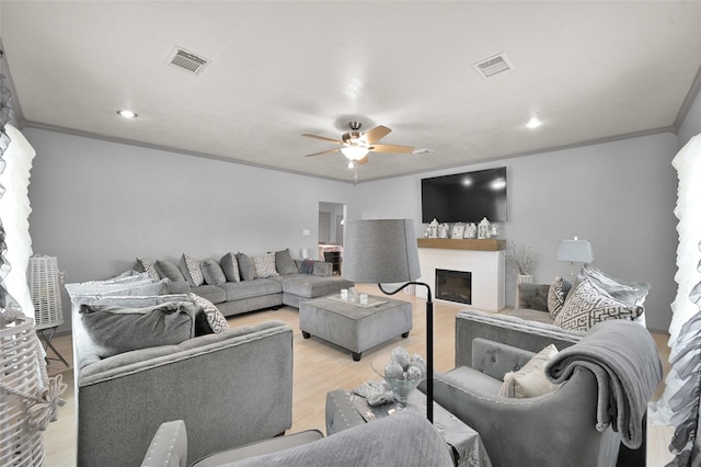 living room with ceiling fan, crown molding, and light hardwood / wood-style flooring