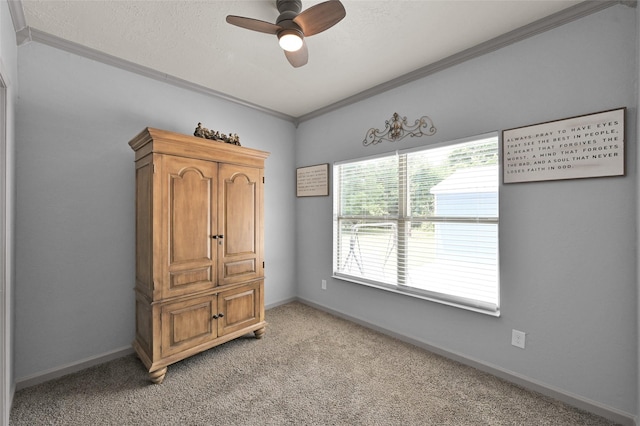 interior space with a textured ceiling, ceiling fan, ornamental molding, and light colored carpet