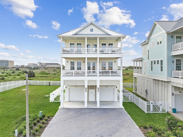 coastal home with a balcony, a front lawn, and a garage