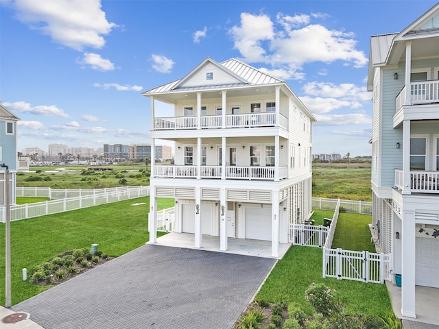 raised beach house featuring a garage, a balcony, and a front yard