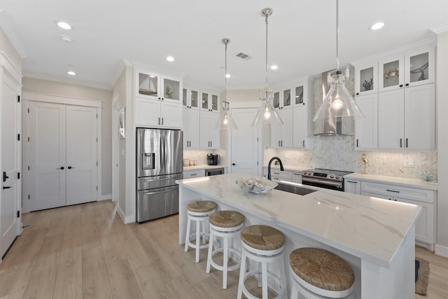 kitchen with white cabinets, an island with sink, pendant lighting, and appliances with stainless steel finishes