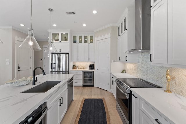 kitchen with white cabinets, appliances with stainless steel finishes, wall chimney exhaust hood, and sink