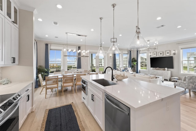 kitchen with pendant lighting, plenty of natural light, an island with sink, and appliances with stainless steel finishes