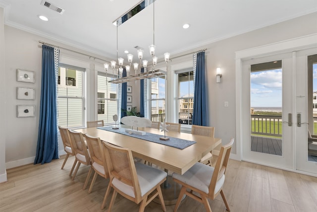 dining space featuring a notable chandelier, french doors, crown molding, and light hardwood / wood-style flooring