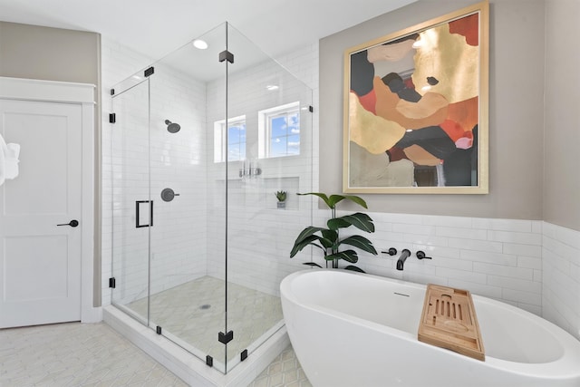 bathroom with tile patterned flooring, tile walls, and plus walk in shower