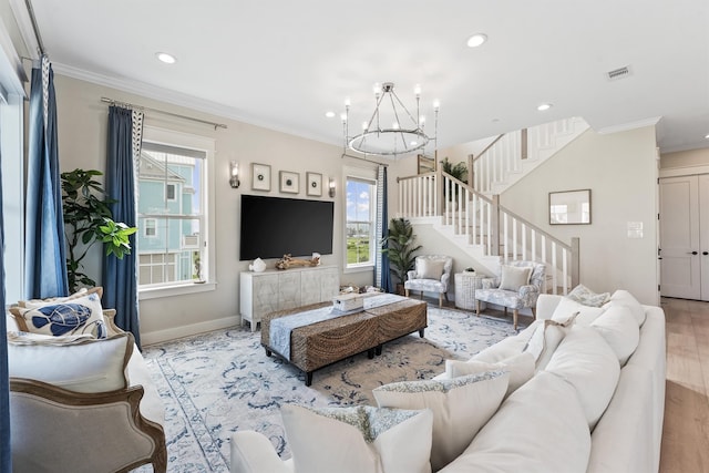 living room with crown molding, a chandelier, and light wood-type flooring