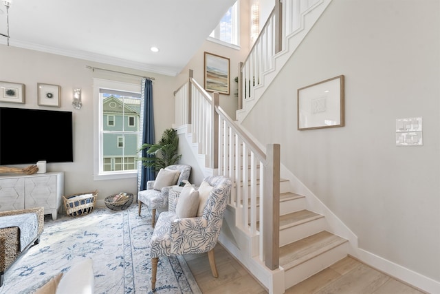 stairs featuring crown molding, plenty of natural light, and hardwood / wood-style floors