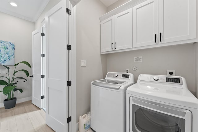 washroom with cabinets, light wood-type flooring, crown molding, and washing machine and clothes dryer