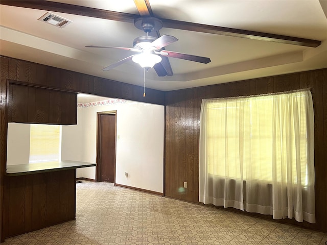 unfurnished room with ceiling fan, a tray ceiling, and beam ceiling