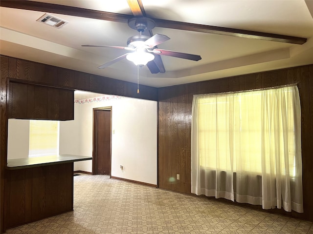 tiled empty room featuring ceiling fan and a raised ceiling