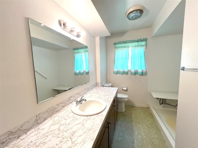 bathroom with a wealth of natural light, tile flooring, toilet, and vanity with extensive cabinet space