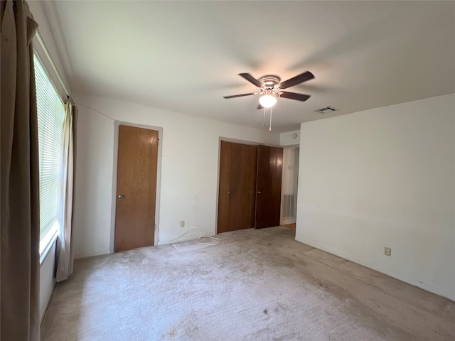 unfurnished bedroom with light carpet, ceiling fan, and multiple windows