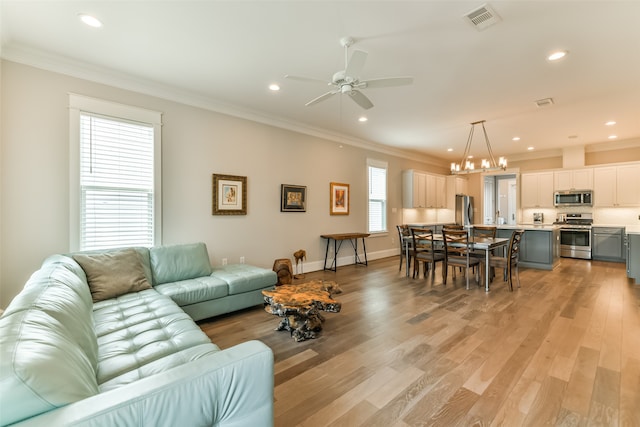 living room featuring light hardwood / wood-style floors, ornamental molding, a healthy amount of sunlight, and ceiling fan