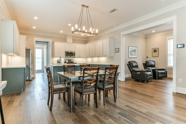 dining space with a chandelier, light hardwood / wood-style flooring, and crown molding