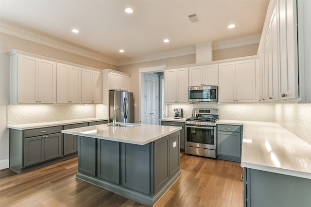 kitchen featuring backsplash, dark wood-type flooring, appliances with stainless steel finishes, and an island with sink