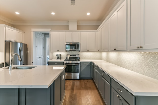 kitchen with stainless steel appliances, hardwood / wood-style floors, ornamental molding, and tasteful backsplash