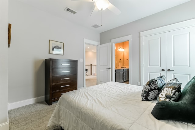 carpeted bedroom with a closet, ceiling fan, and ensuite bath