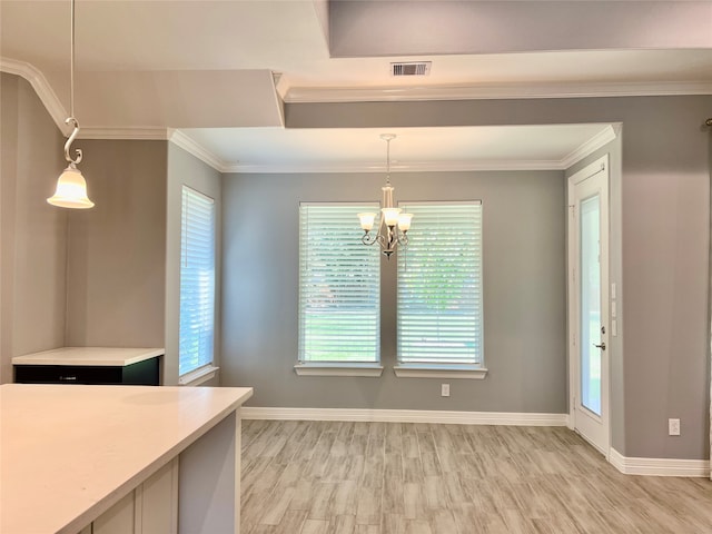 unfurnished dining area featuring light wood-type flooring, a chandelier, and ornamental molding