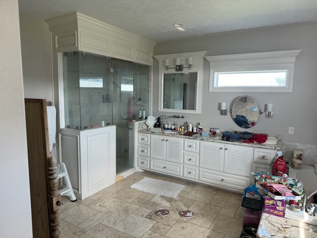 bathroom featuring a shower with door, tile flooring, a textured ceiling, and vanity with extensive cabinet space