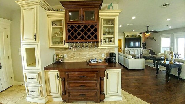 bar with cream cabinets, backsplash, ceiling fan, and light tile floors