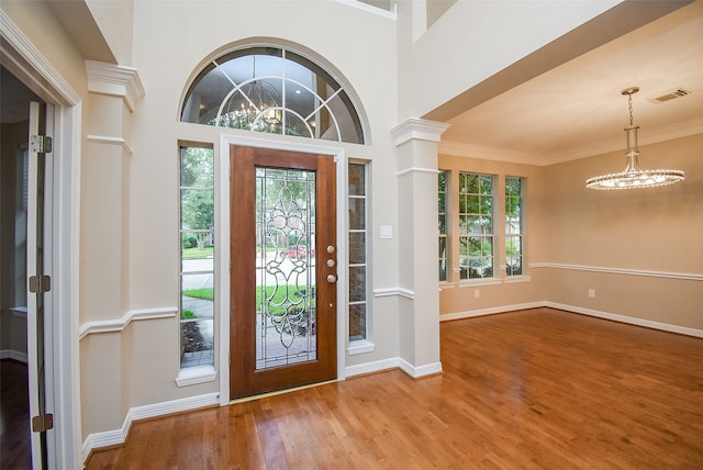 foyer featuring ornamental molding, a high ceiling, an inviting chandelier, and hardwood / wood-style floors