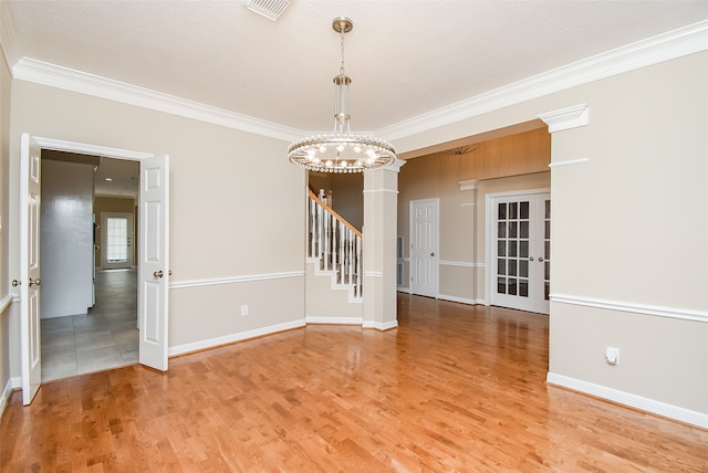 empty room with a notable chandelier, a textured ceiling, hardwood / wood-style floors, and crown molding