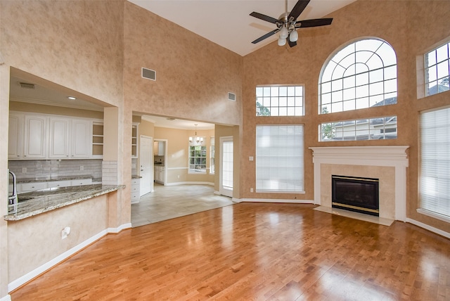 unfurnished living room with a high ceiling, light hardwood / wood-style floors, and a wealth of natural light