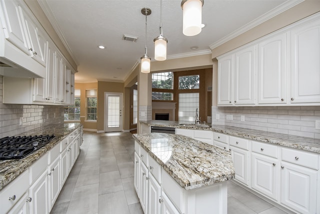 kitchen featuring decorative backsplash, a kitchen island, decorative light fixtures, a healthy amount of sunlight, and sink